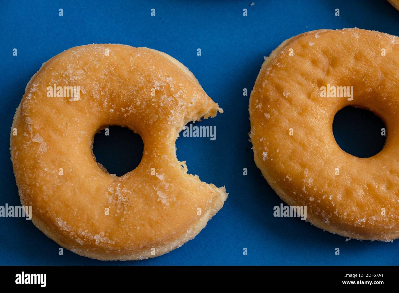 Donut mordido sobre fondo azul. Foto de stock