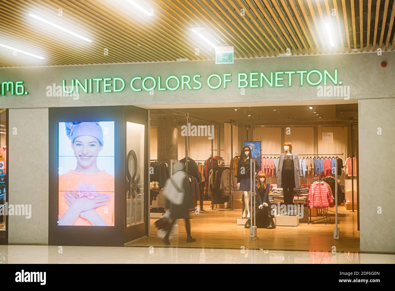 Mujer caminando cerca de United Colors de Benetton Store en las tiendas  Centro comercial Fotografía de stock - Alamy