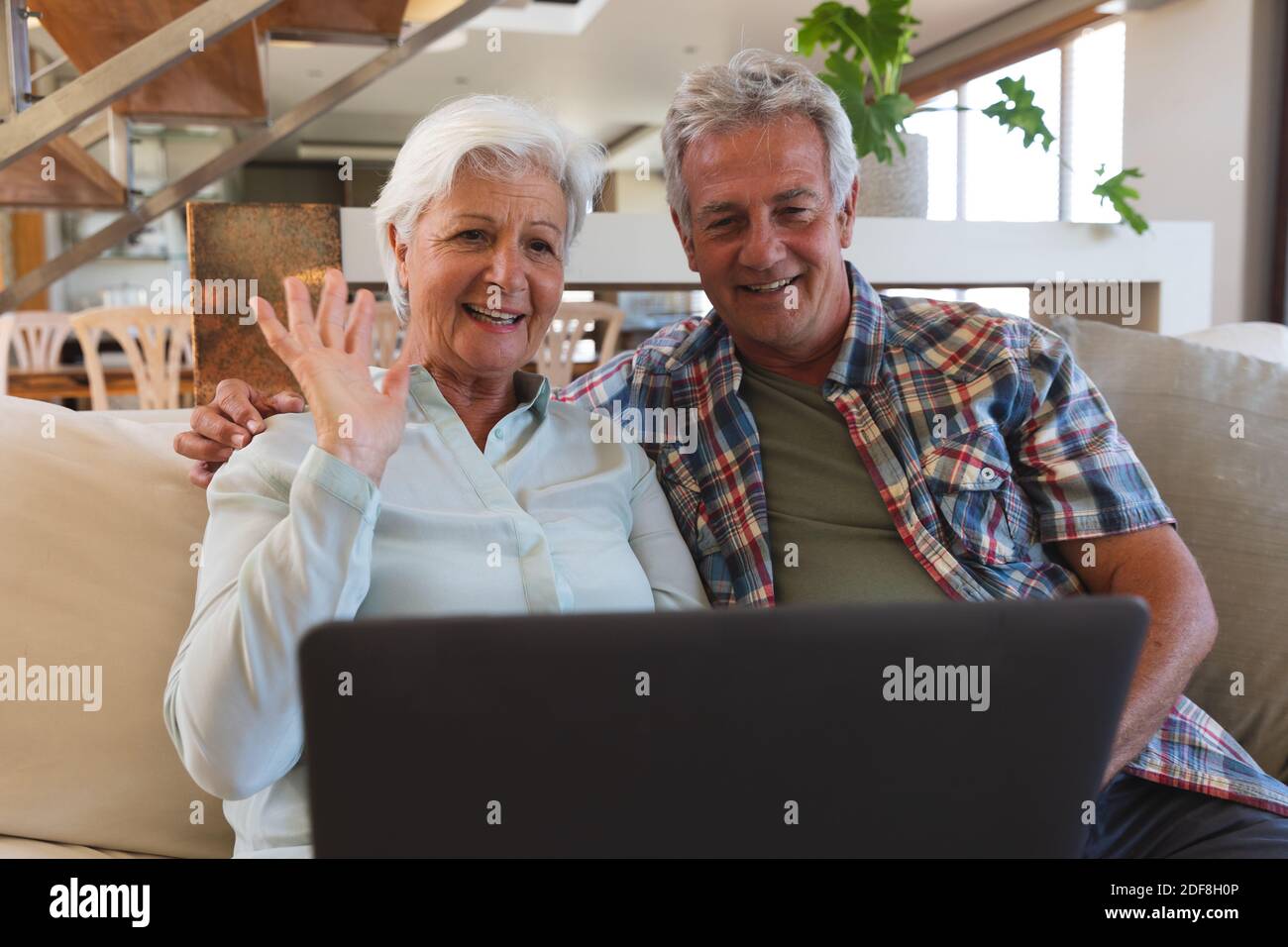 Pareja caucásica mayor en videollamada sonriendo y agitando Foto de stock