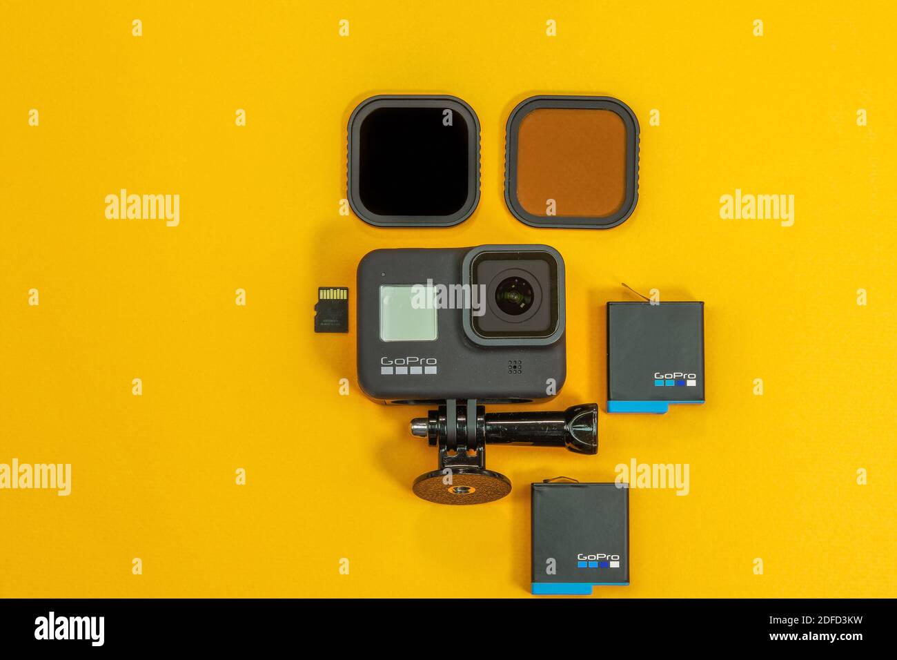 GoPro 8 negro con logo y accesorios vista superior. Cámara de acción plana  con tarjeta de memoria y batería de fondo amarillo con filtros de lente en  la mesa Fotografía de stock -