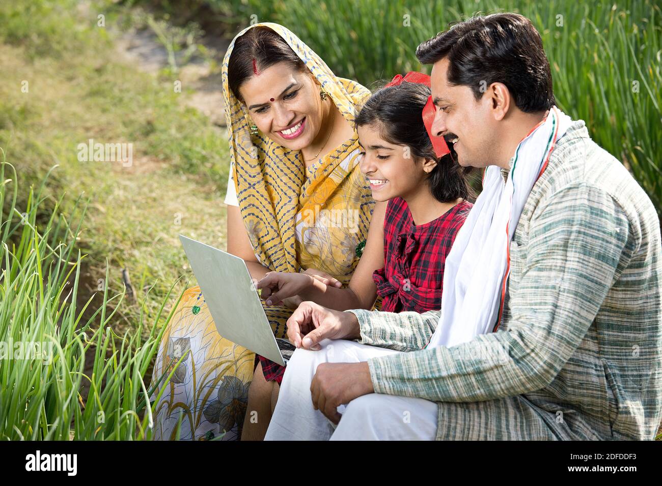 Familia rural utilizando ordenador portátil en el campo agrícola Foto de stock