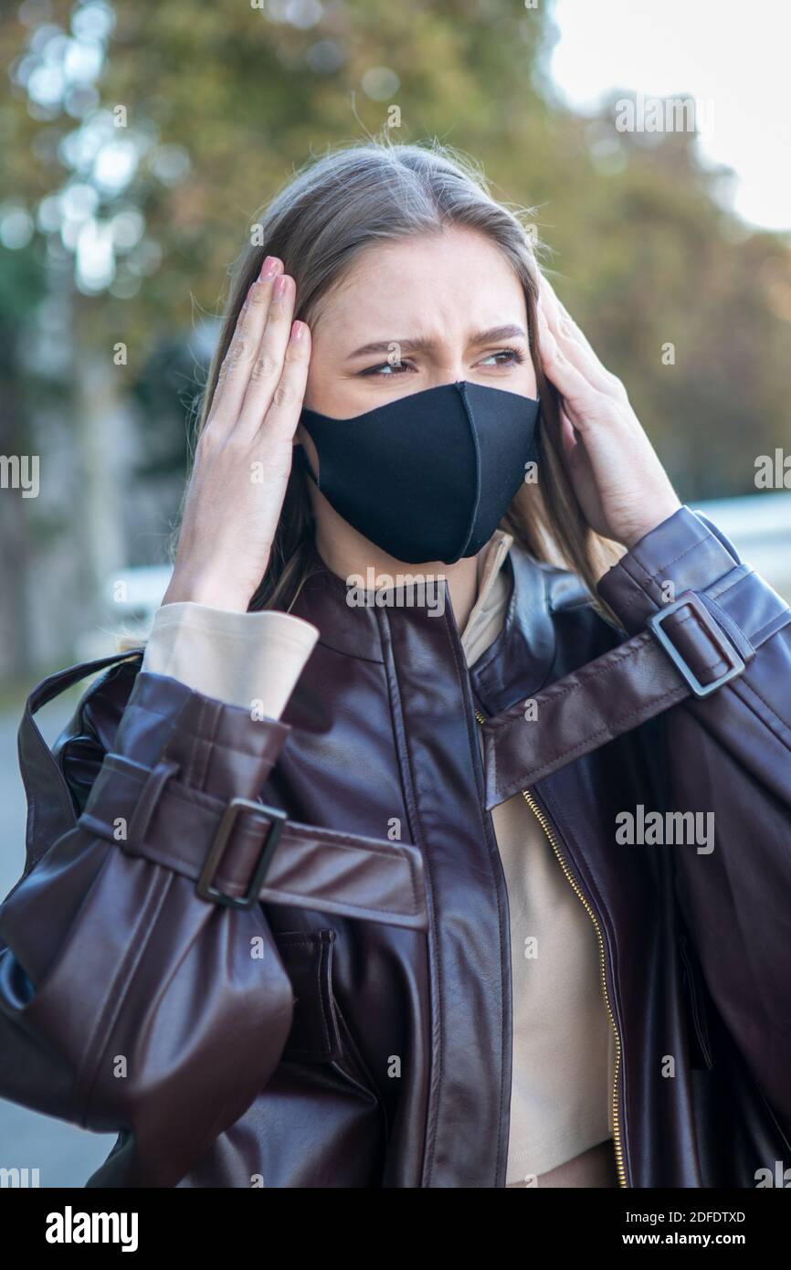 Mujer con mascarilla protectora con dolor de cabeza Foto de stock