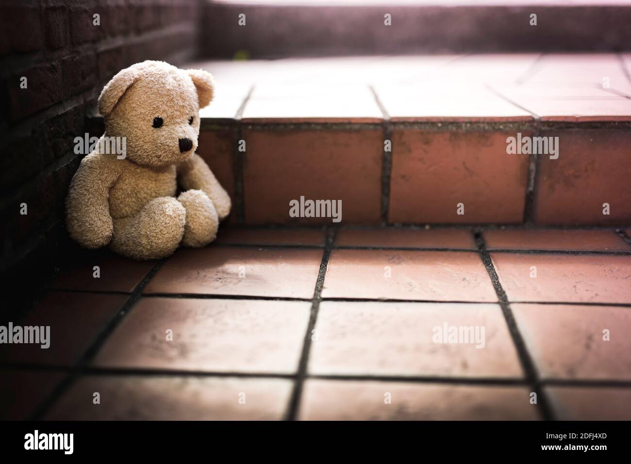 Oso de peluche solitario sentado en el suelo, Trauma infantil Foto de stock
