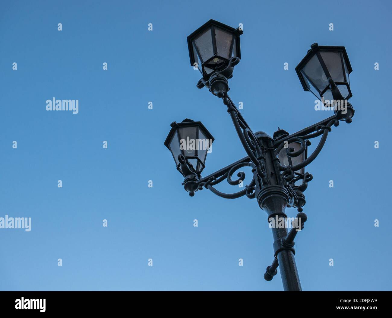 Una vieja lámpara callejera de hierro fundido con cuatro hermosas lámparas Foto de stock