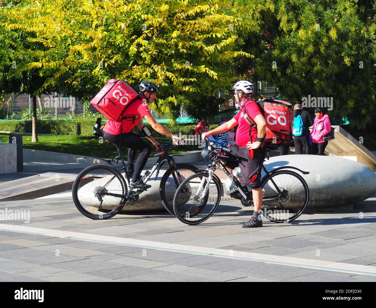 Budapest, Hungría : 09 de octubre de 2020: Dos mensajeros de entrega de bicicletas con bicicleta en ropa roja y mochilas hablando en la plaza mientras se toma un descanso Foto de stock
