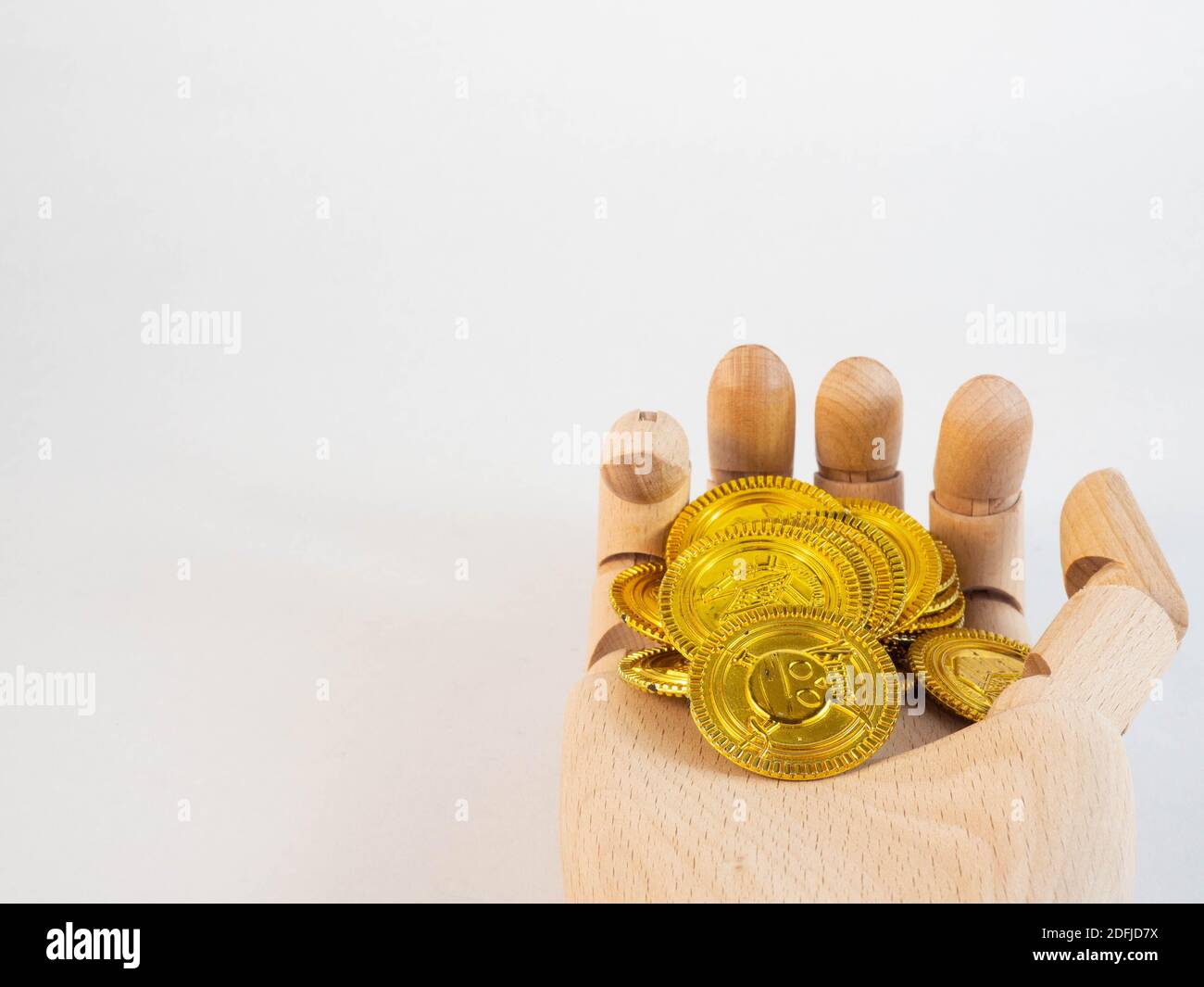 Una mano de madera sobre una pila de monedas de oro. Concepto de dinero e inversión. Foto de stock