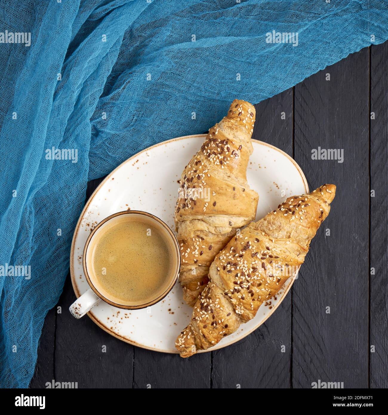 Croissants frescos y una taza de café sobre mesa negra. Espacio de copia, vista superior Foto de stock