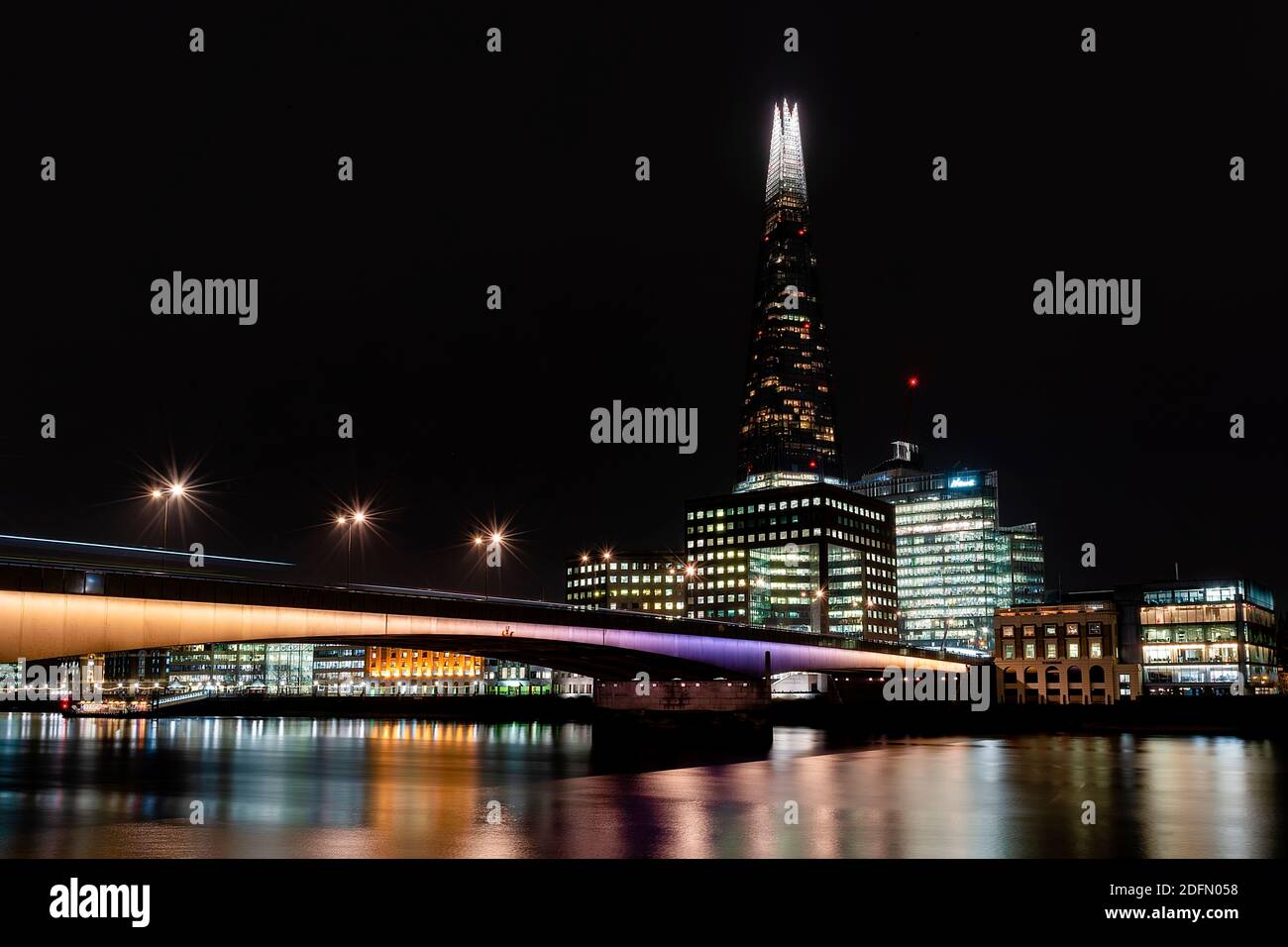 Londres, Reino Unido - Ene 2020: El Shard y el puente de Londres iluminados y reflejando en el Támesis. Exposición prolongada. Foto de stock