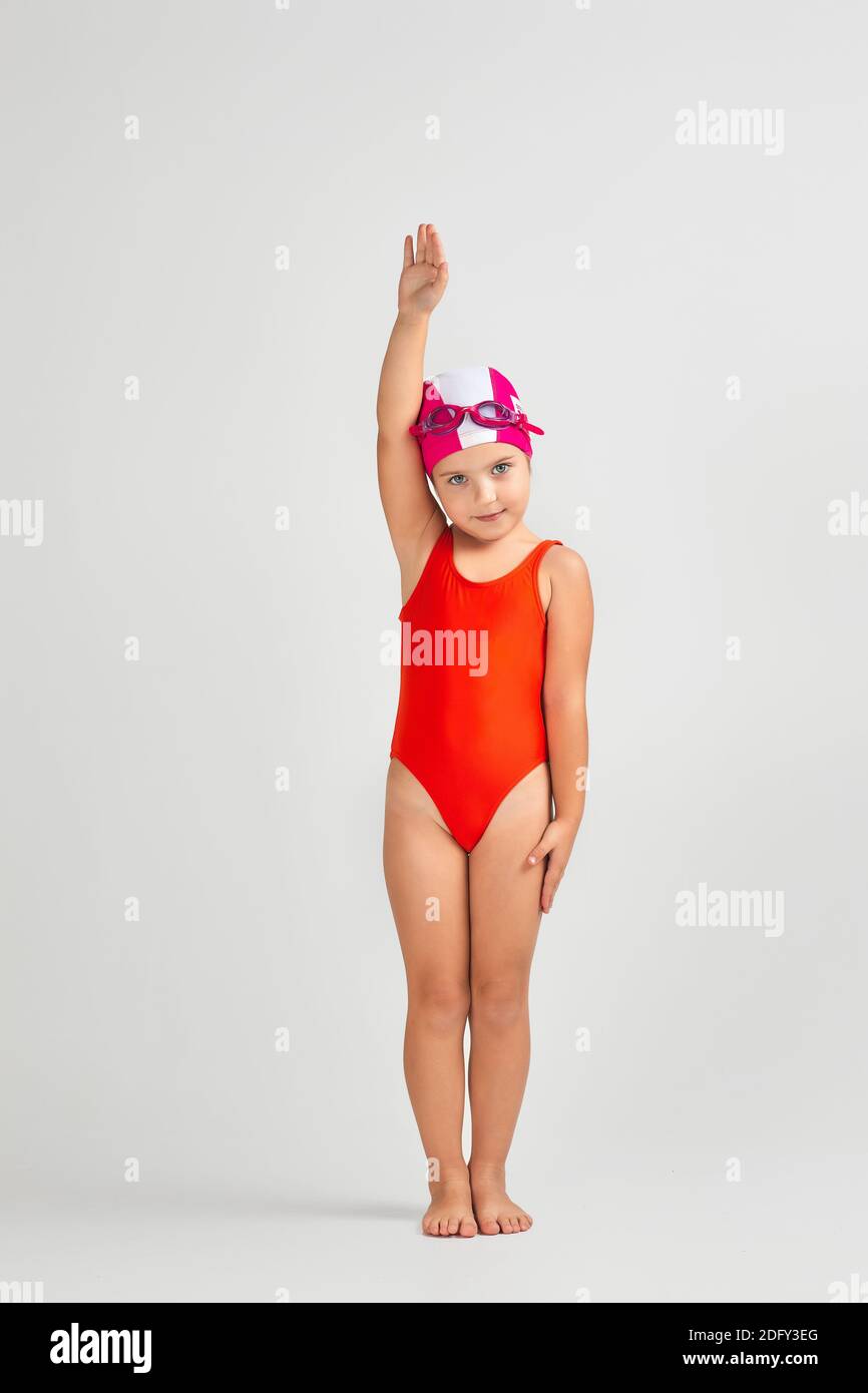 niña pequeña en traje de baño, gafas de natación y gorro de baño se está  preparando para nadar. El niño sueña con convertirse en un campeón de  natación Fotografía de stock -