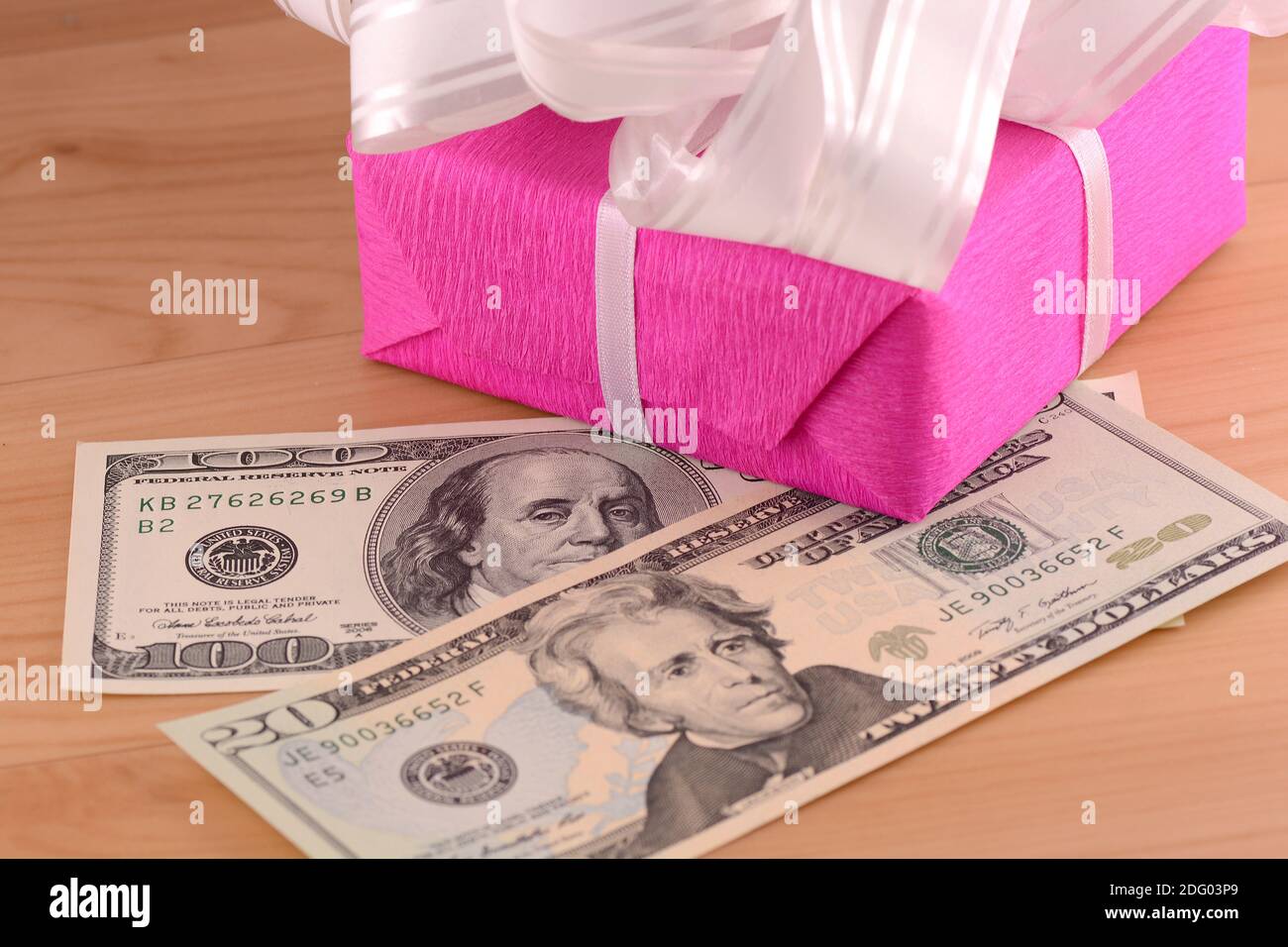 Dólares dinero junto con un regalo, un símbolo de la crisis, la venalidad, el acaparamiento y la riqueza. Dinero americano sobre fondo de madera. Foto de stock