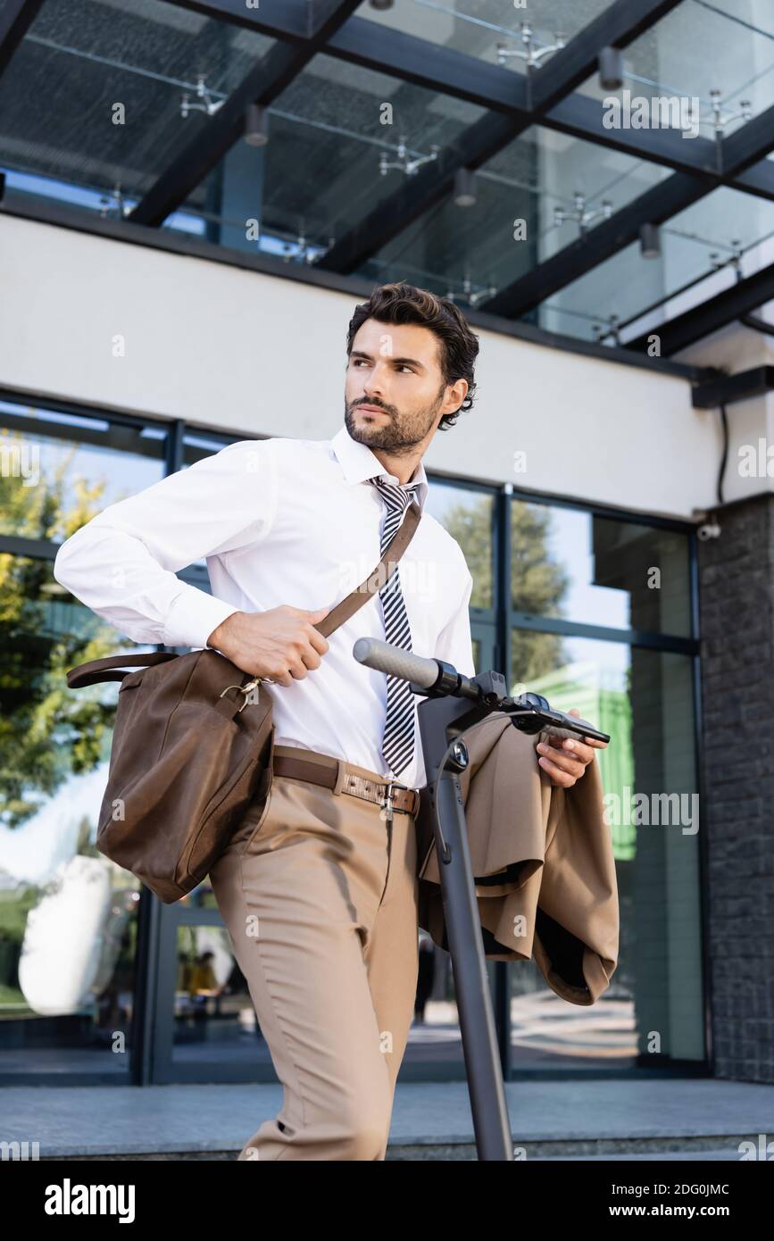 hombre de negocios en ropa formal con bolsa de cuero de pie cerca