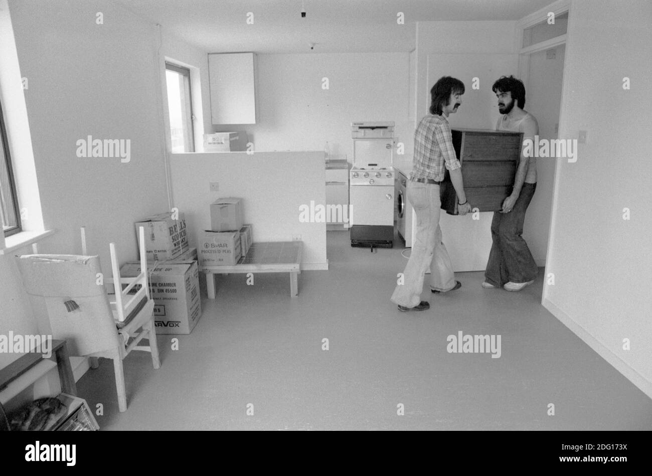 Mudando casa, mudando hombres llevando muebles a una nueva casa familiar. 1977. 1970 REINO UNIDO HOMER SYKES Foto de stock