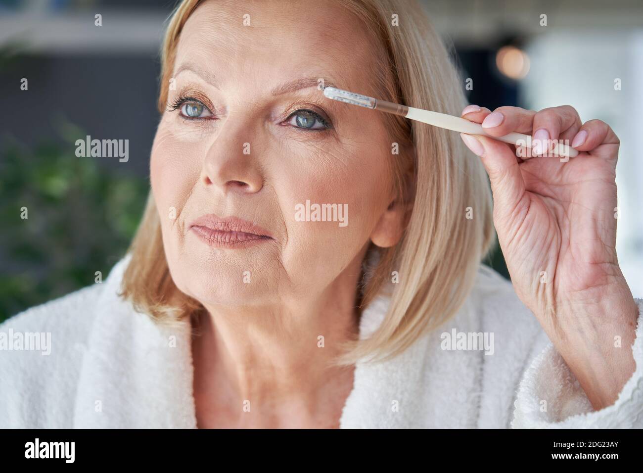 Mujer mayor aplicando maquillaje en el baño Fotografía de stock - Alamy