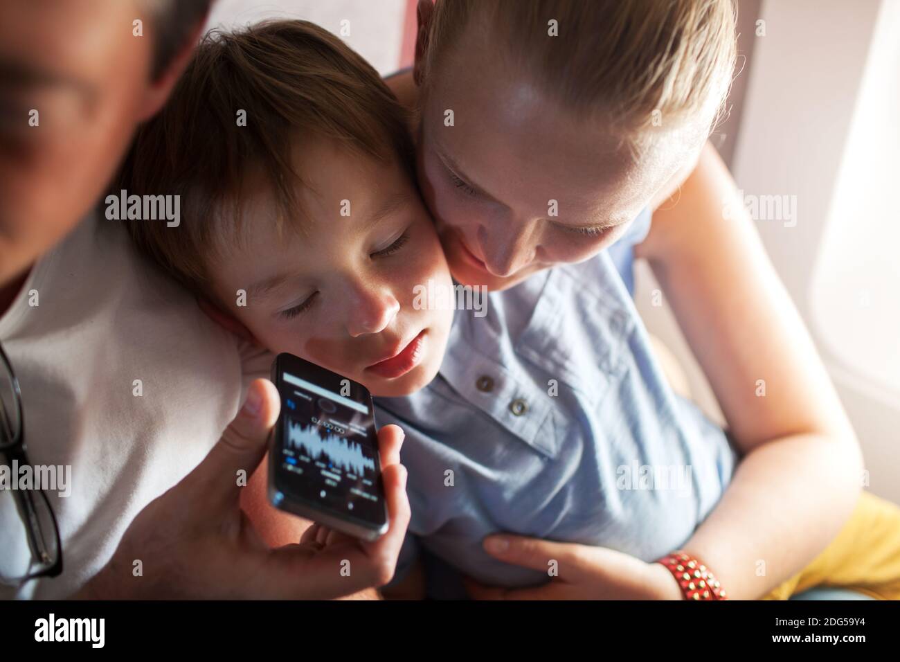 Niño durmiendo con música en el teléfono móvil en el avión Foto de stock