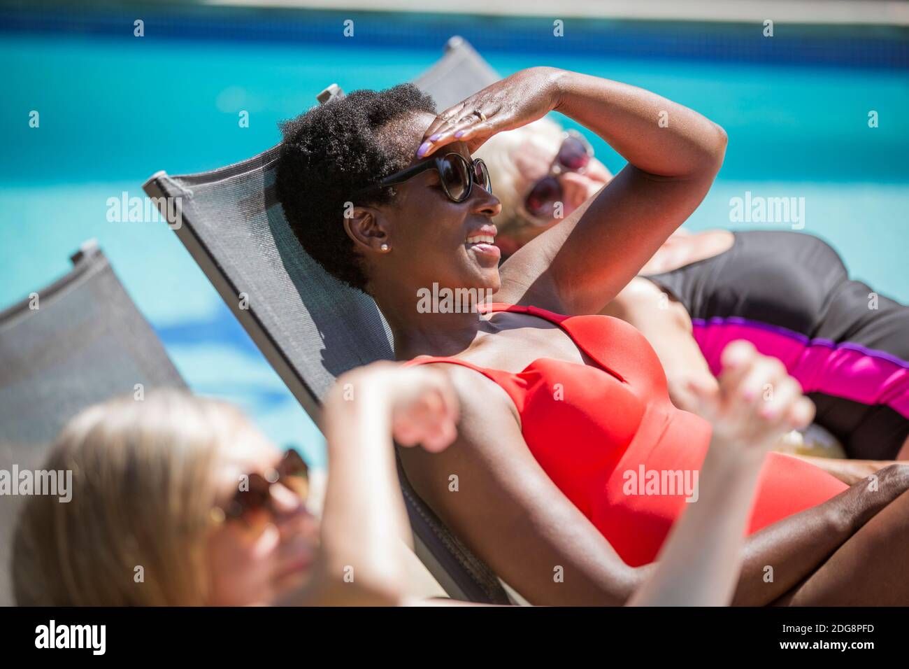 Felices amigas soleadas en verano junto a la piscina Foto de stock