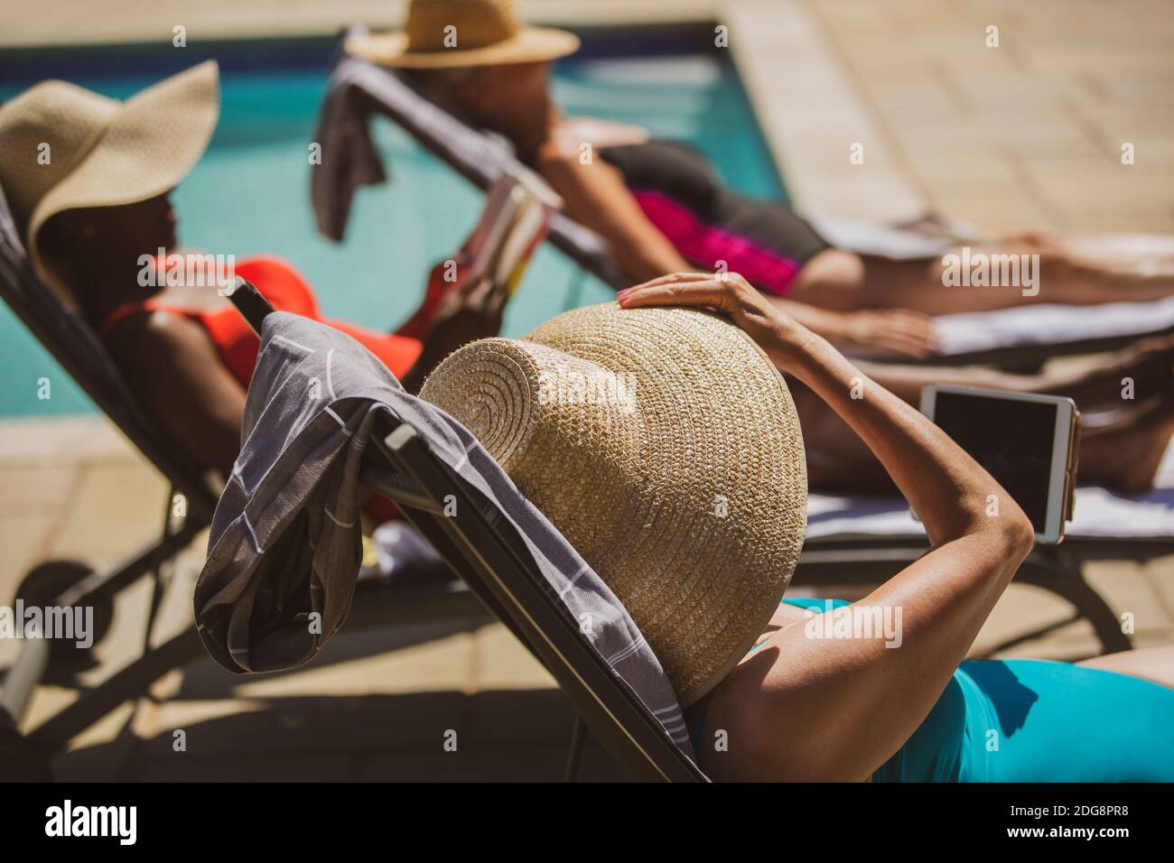 Mujeres amigas soleadas en verano junto a la piscina Foto de stock