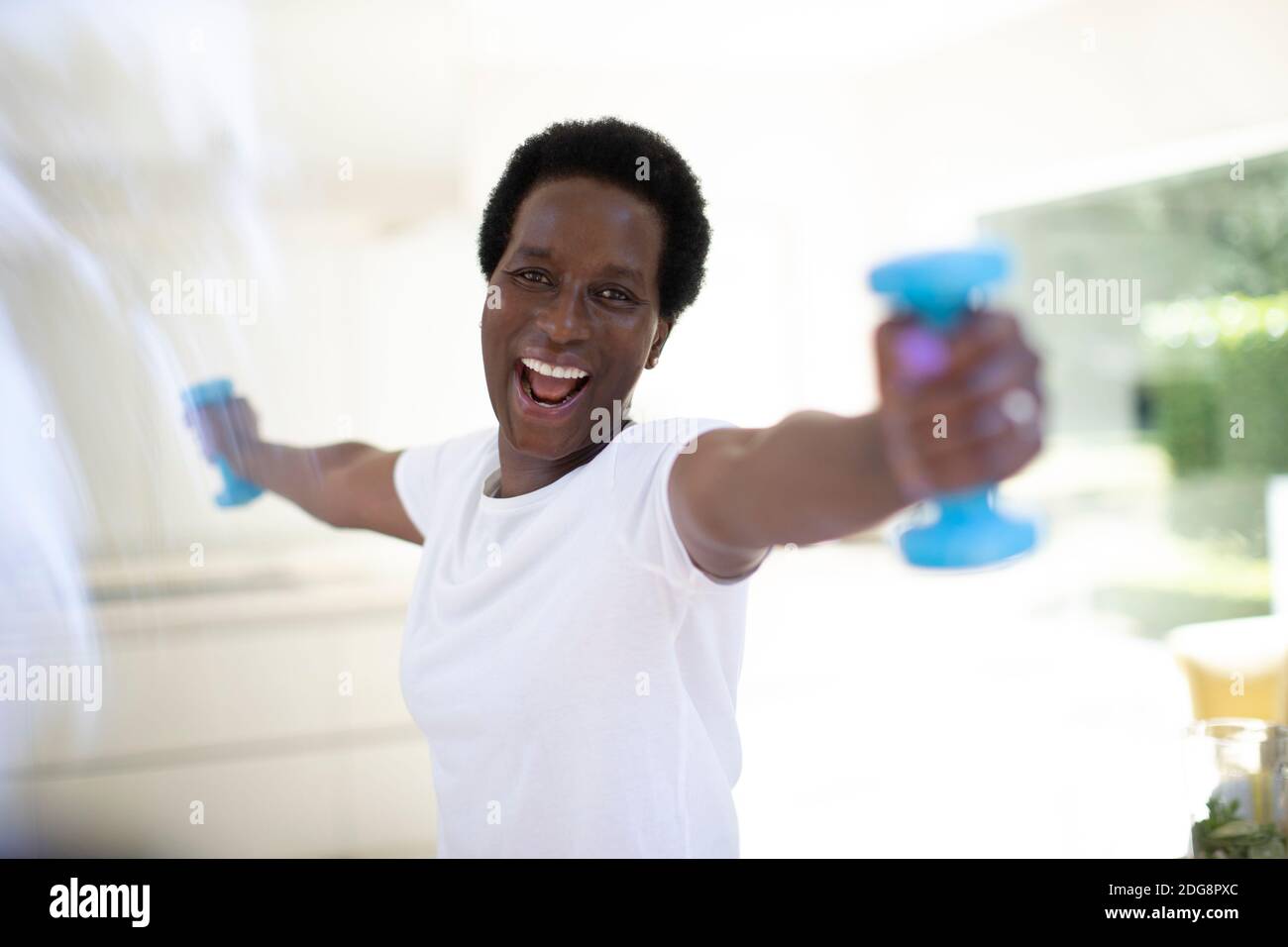 Retrato mujer madura y energética haciendo ejercicio con pesas en casa Foto de stock