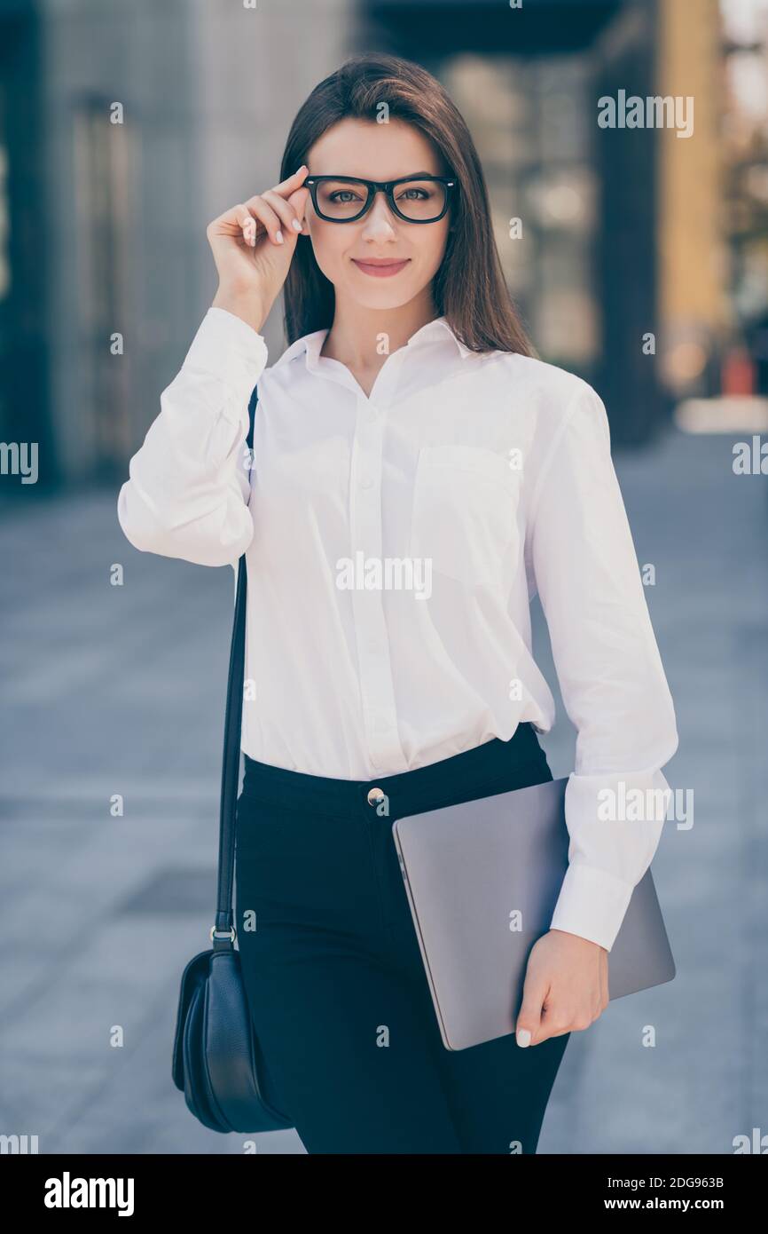 Foto vertical de encantadora señorita vestida camisa blanca formal brazo  gafas bolso de mano sosteniendo el dispositivo moderno fuera Fotografía de  stock - Alamy