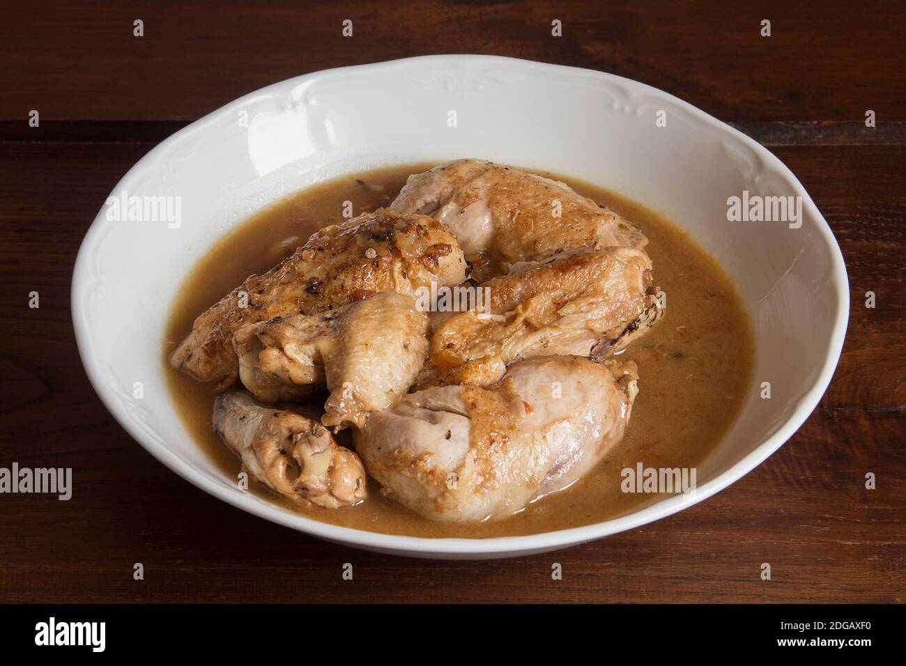 Presentación enchapado de pollo en salsa de verduras con coñac sobre una mesa de madera. Cocinar recetas en casa. Carne y verduras. Foto de stock