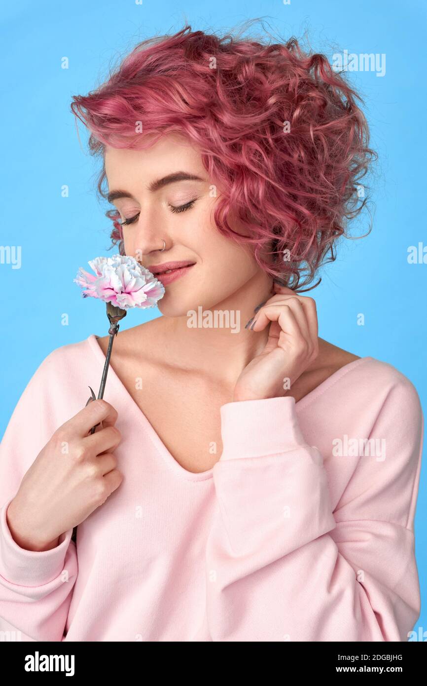 Bonita chica sonriente con cabello rizado rosa y nariz perfora la flor de  la clavel y disfrutar de la fragancia sobre fondo azul. Freestyle, flor sh  Fotografía de stock - Alamy