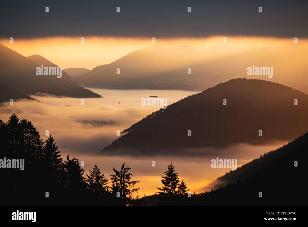 Picos de montaña a través de la alfombra de nubes al amanecer, Salzburgo, Austria Foto de stock