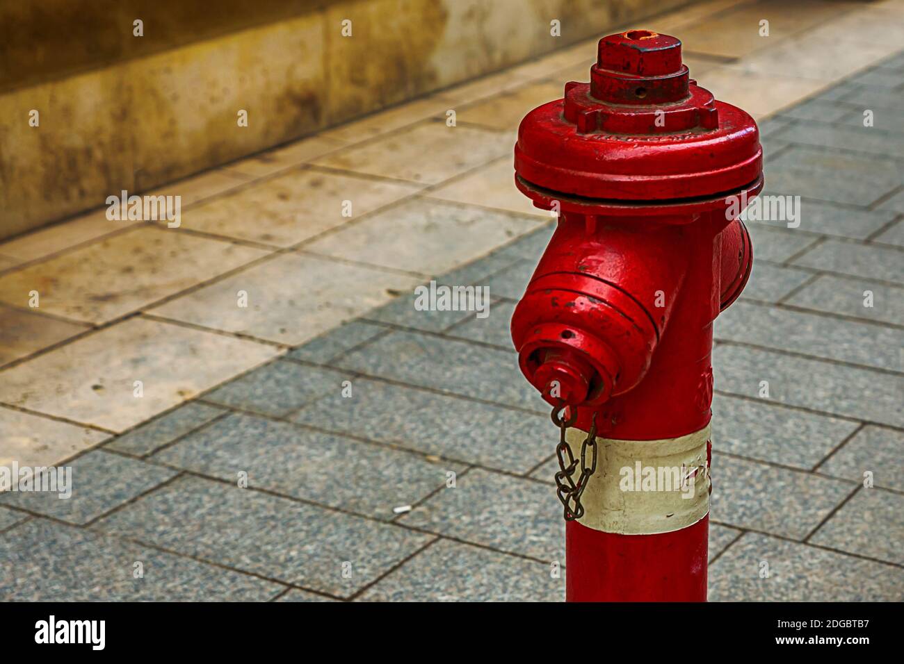 Hidrante de fuego rojo blanco protección de la ciudad en un fondo de azulejos grises diseño urbano Foto de stock