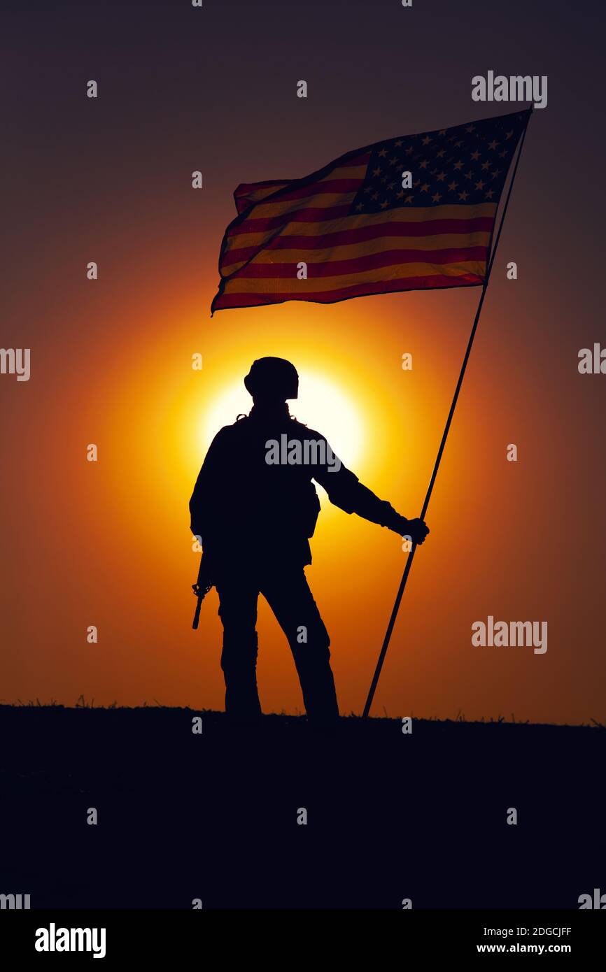 Silueta del soldado de infantería del ejército de EE.UU., caza del cuerpo de Marines de los Estados Unidos de pie en el horizonte de la puesta de sol con la bandera nacional de EE.UU. Que ondea. Soldados heroísmo y victoria en la batalla, honrando a los héroes caídos Foto de stock