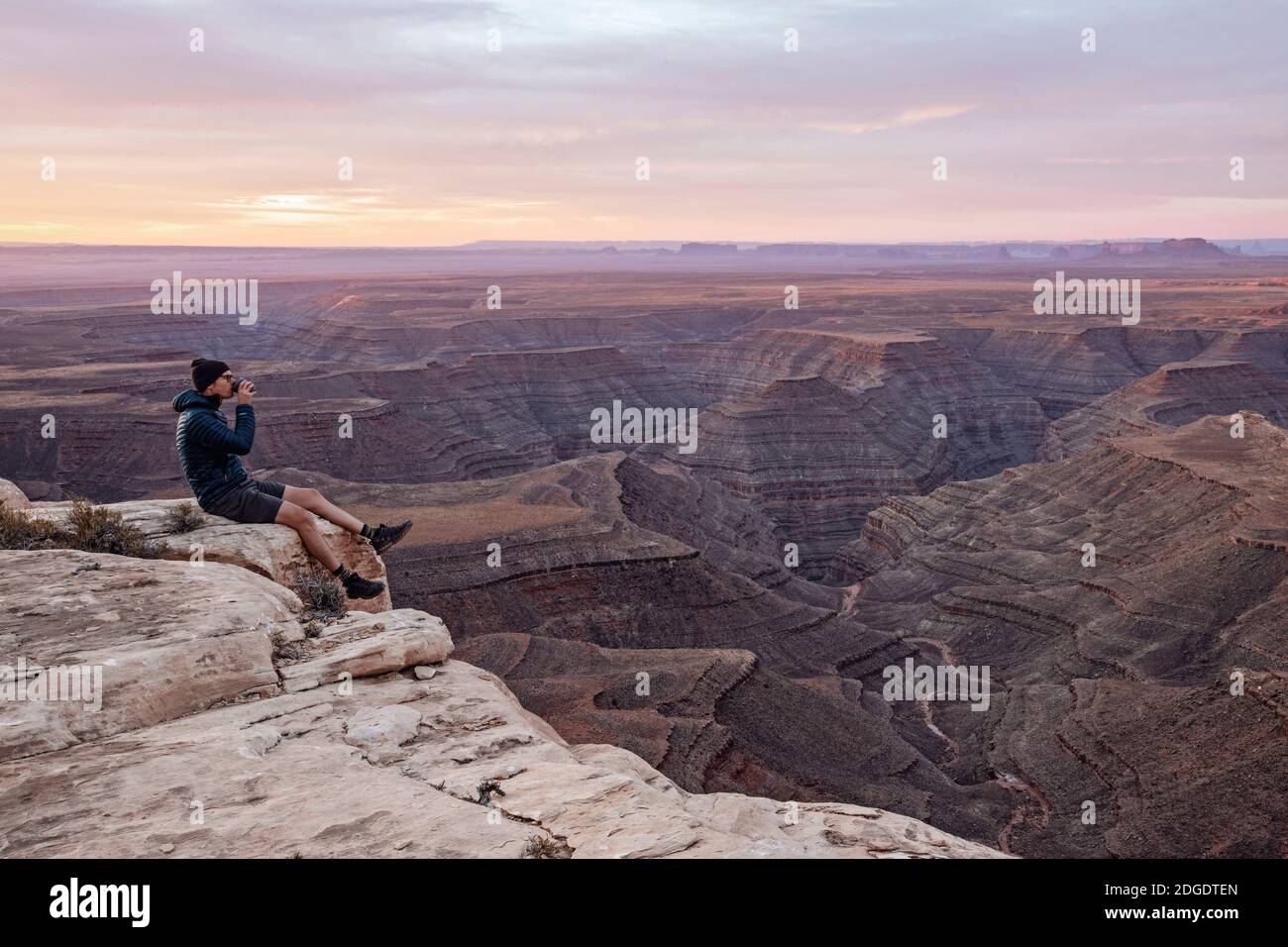 El hombre bebe café sentado en el borde del acantilado, sombrero mexicano, Utah Foto de stock