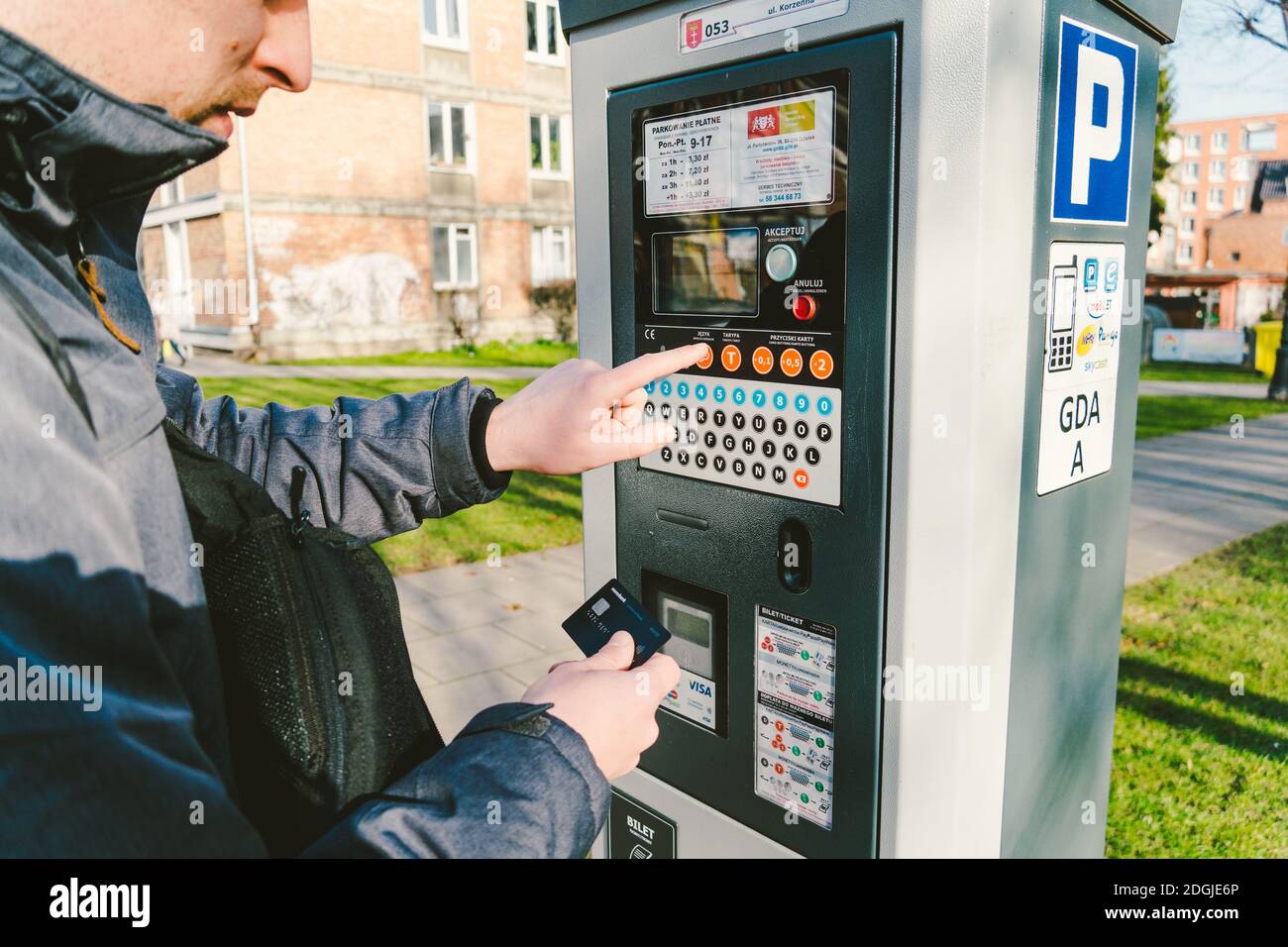 El hombre paga por el aparcamiento con una tarjeta de crédito con tecnología NFS. Pago fácil. Proceso de pago en terminal de estacionamiento de máquinas. Hombres de pago Foto de stock
