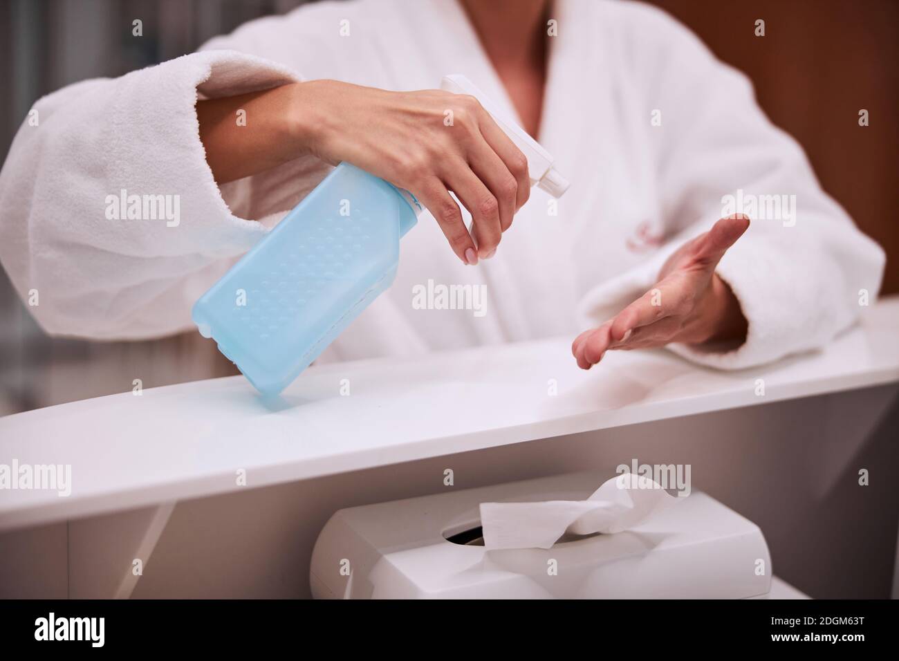 Mujer desinfectando sus manos en el mostrador de recepción del salón de belleza Foto de stock