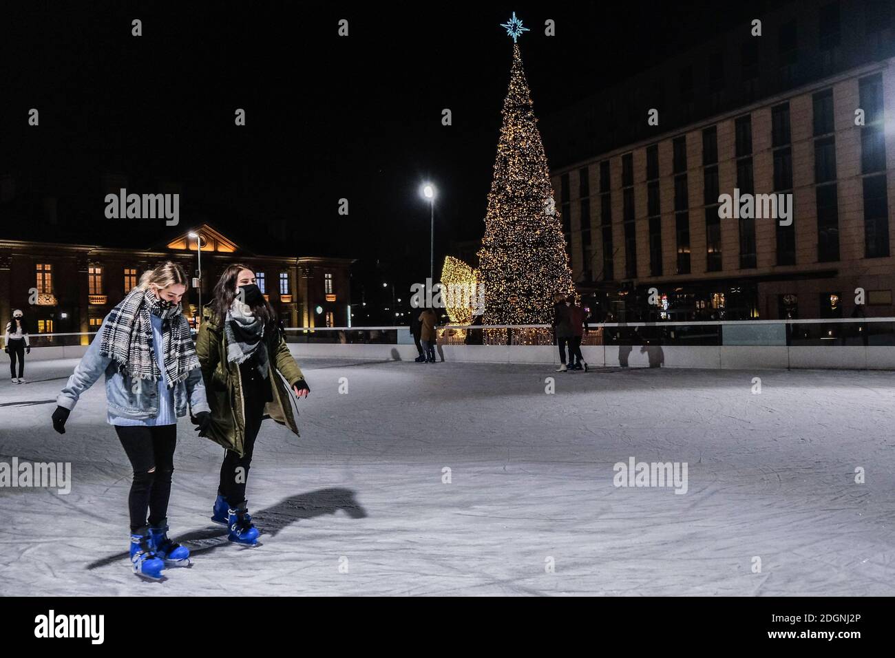 Cracovia, Polonia. 08 de diciembre de 2020. Un par de damas vieron patinaje sobre hielo junto a un árbol de Navidad gigante frente al centro comercial Krakowska. El mercado de Navidad más grande y popular de Cracovia se celebra en el centro histórico de la ciudad, el casco antiguo de Cracovia, en la plaza principal del mercado. Es uno de los primeros lugares elegidos para la lista original del Patrimonio Mundial de la UNESCO. Crédito: SOPA Images Limited/Alamy Live News Foto de stock