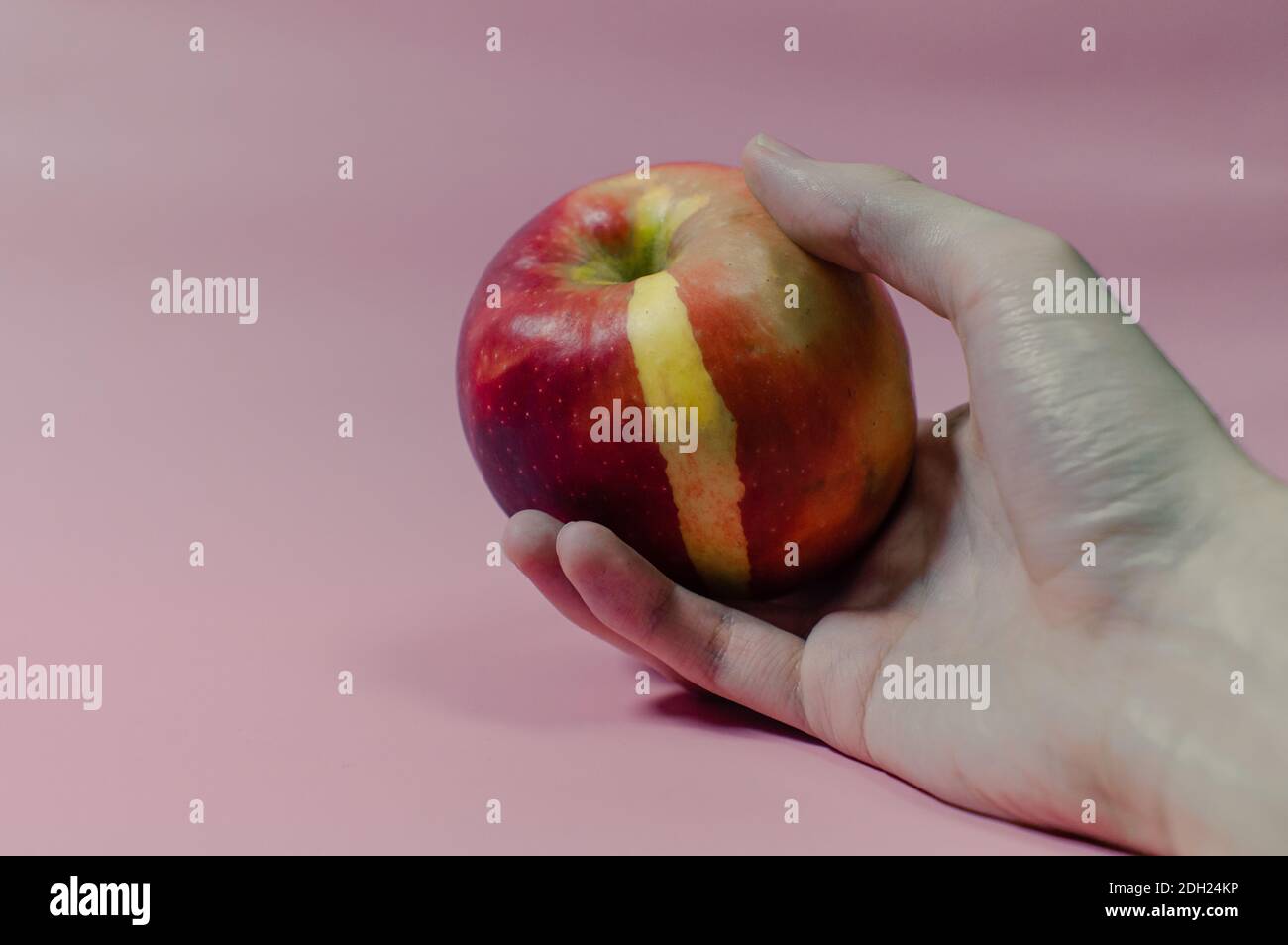 Una manzana roja envenenada en una mano caída Foto de stock