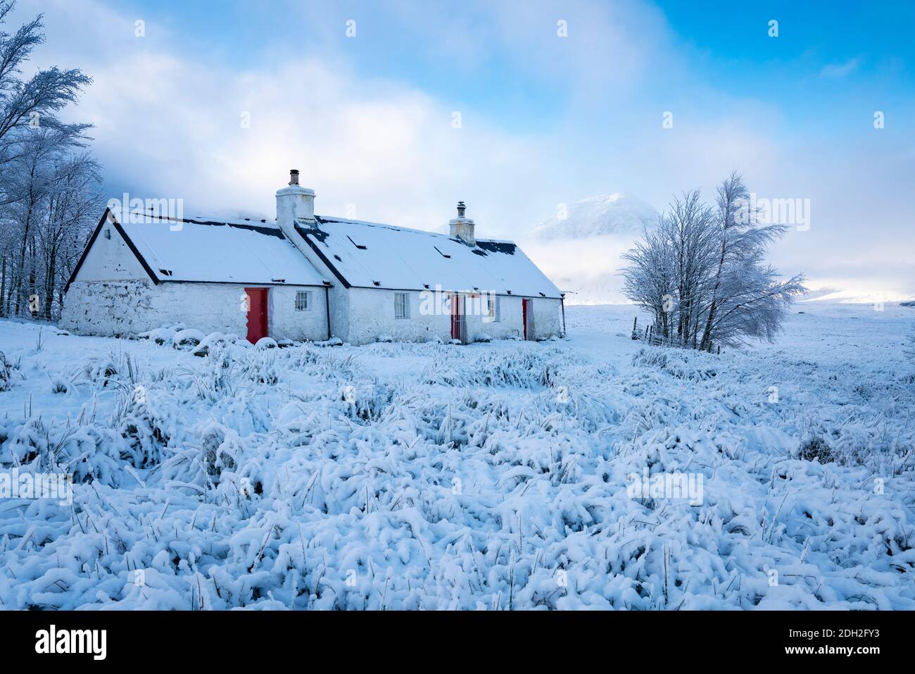 Blackrock Cottage cubierto de nieve con niebla Buachaille Etive Mor en la distancia en invierno, Glen Coe, Escocia, Reino Unido Foto de stock