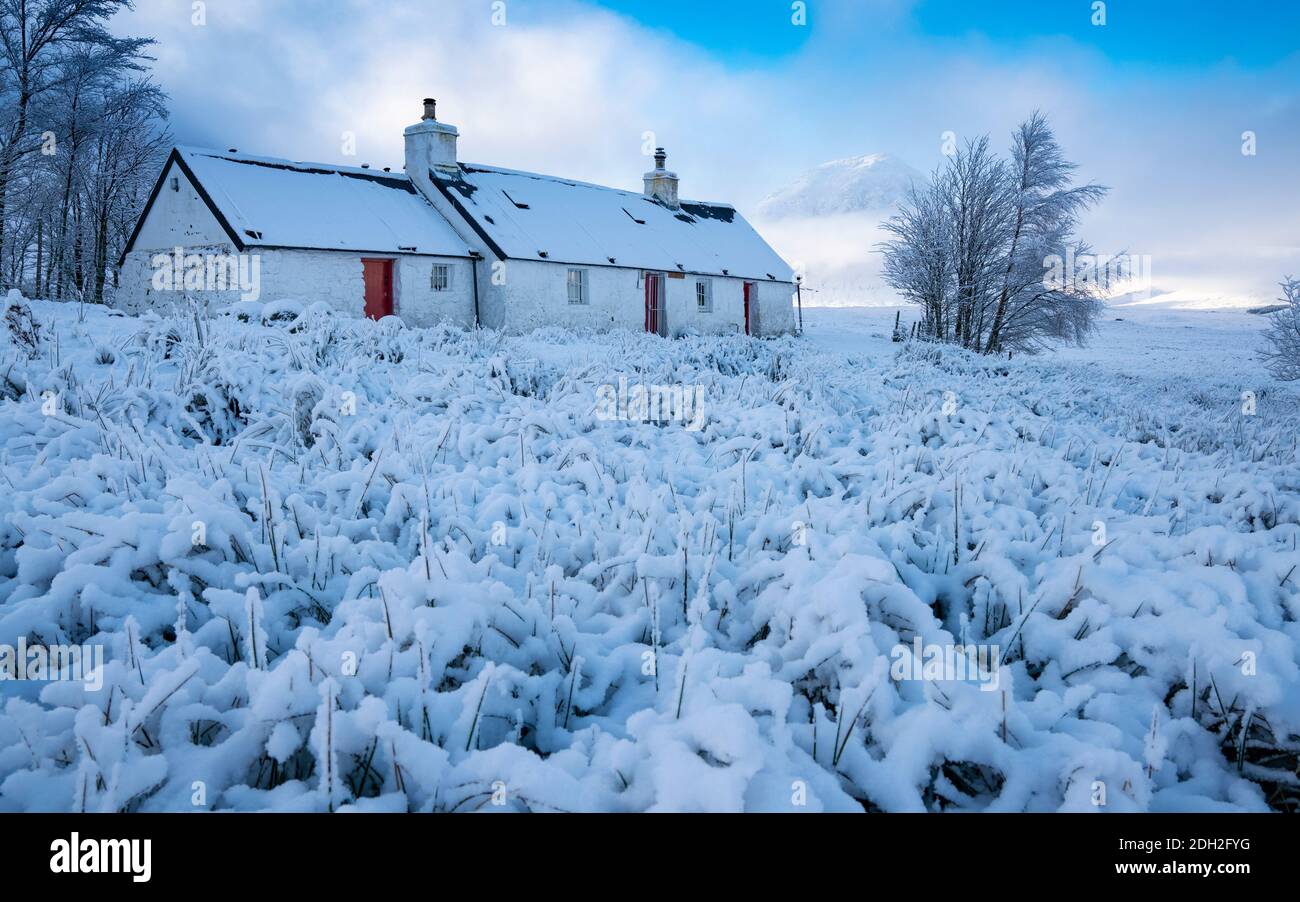 Blackrock Cottage cubierto de nieve con niebla Buachaille Etive Mor en la distancia en invierno, Glen Coe, Escocia, Reino Unido Foto de stock