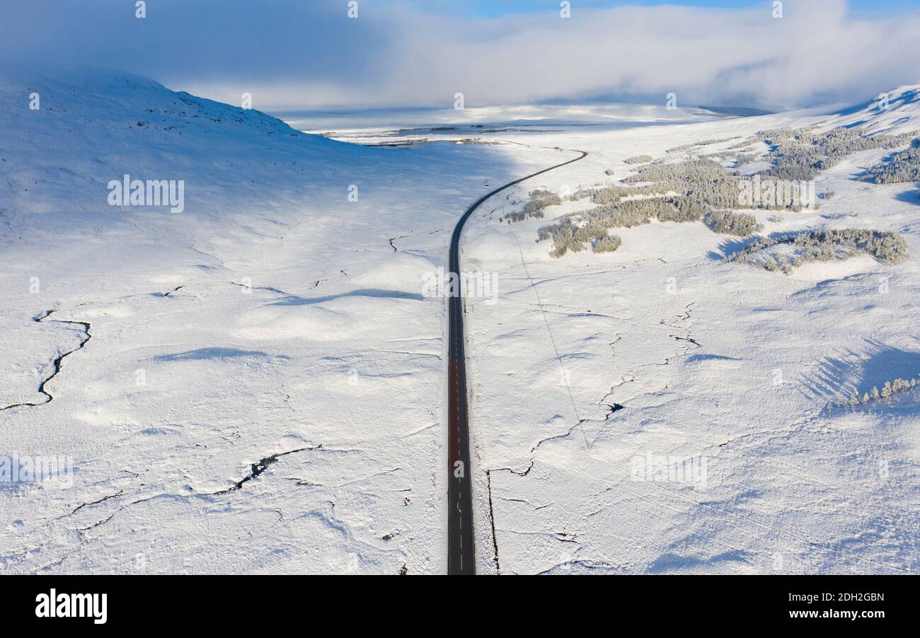 Vista aérea de la carretera A82 cruzando Rannoch Moor cubierto de nieve durante el invierno, Highlands, Escocia, Reino Unido Foto de stock