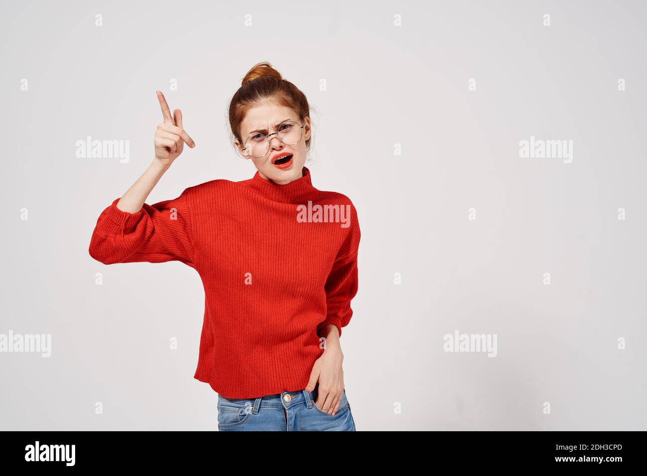 hermosa mujer en el suéter rojo gestuando con sus manos y.. vaqueros modelo  fondo claro Fotografía de stock - Alamy