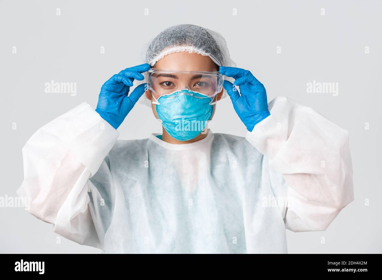 Covid-19, enfermedad de coronavirus, concepto de trabajadores de la salud. Médico asiático de aspecto serio en equipo de protección personal, Foto de stock