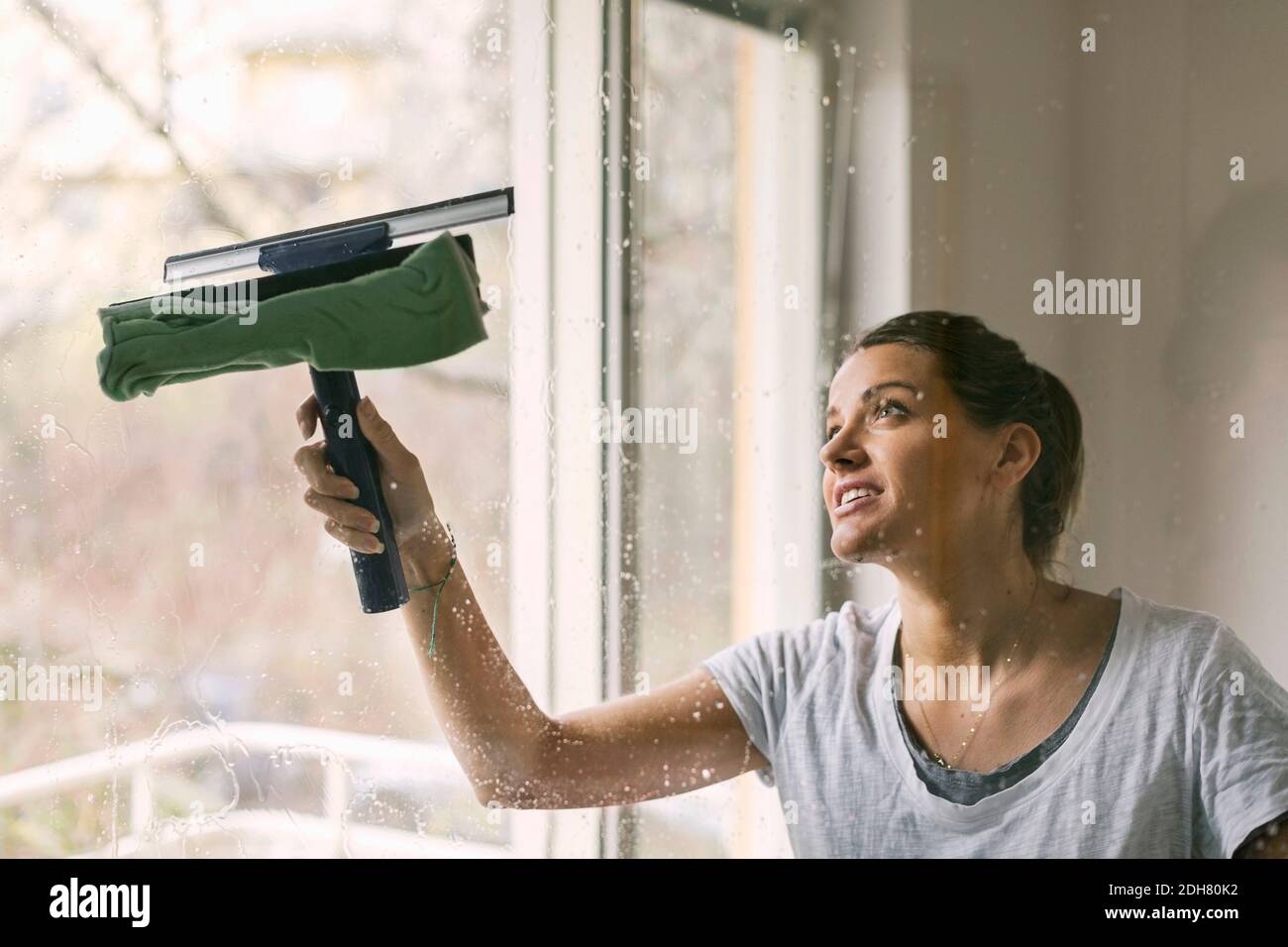 Mujer limpiando la ventana de cristal Foto de stock