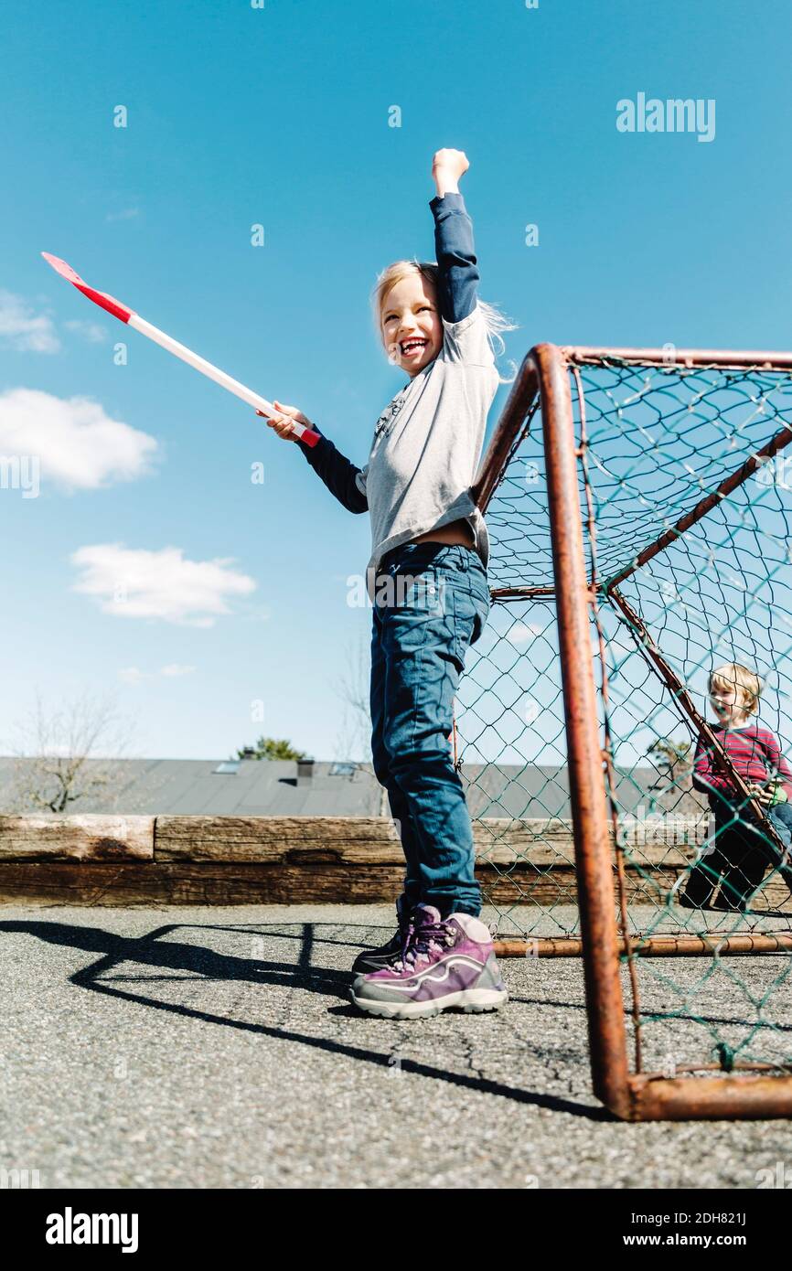 Vista de ángulo bajo de éxito chica que sostiene palo de hockey contra cielo azul Foto de stock