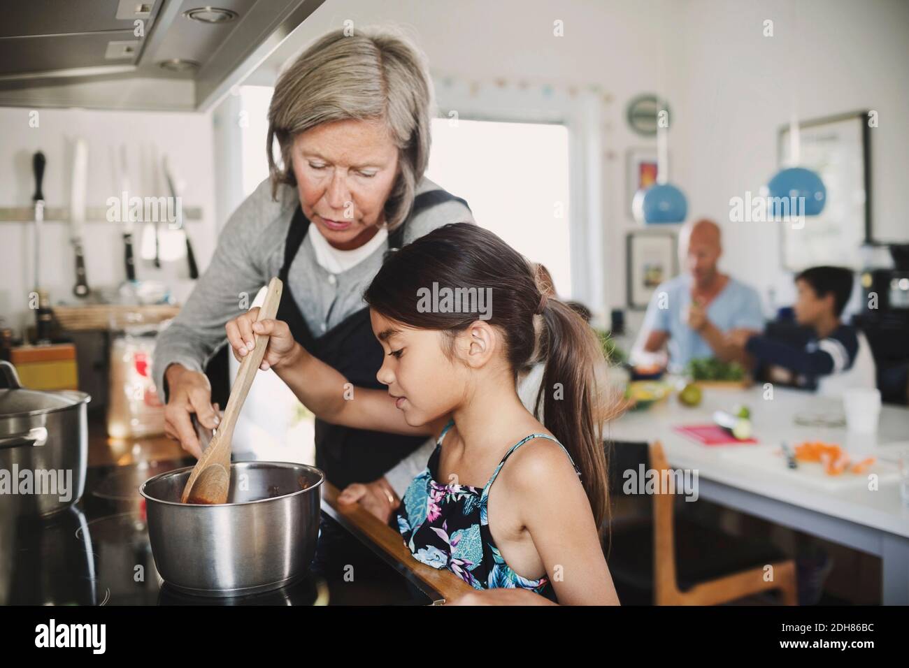 Abuela mirando a la chica cocinando en el mostrador de la cocina Foto de stock