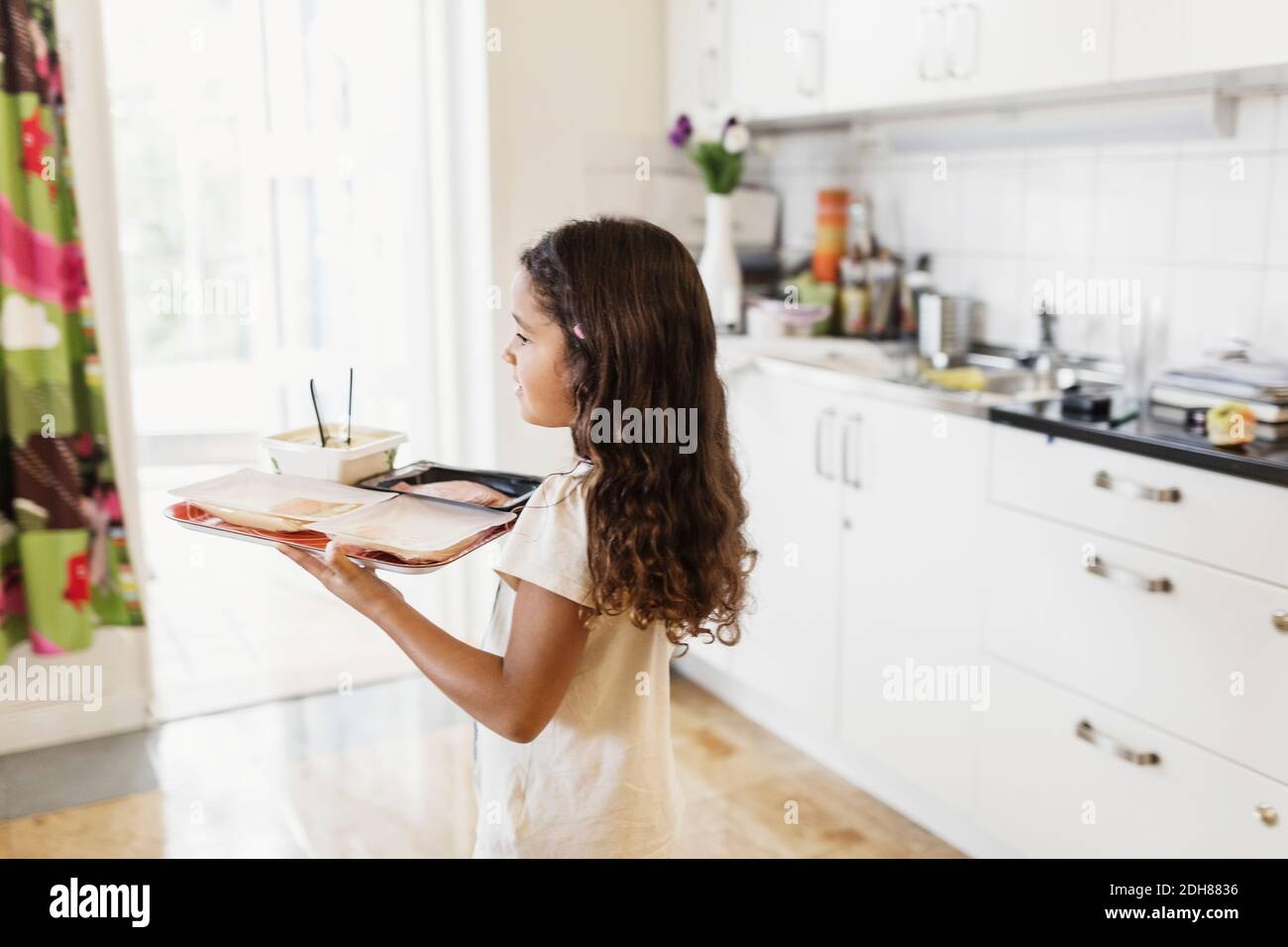 Niña llevando comida en bandeja en el centro de cuidado de día Foto de stock