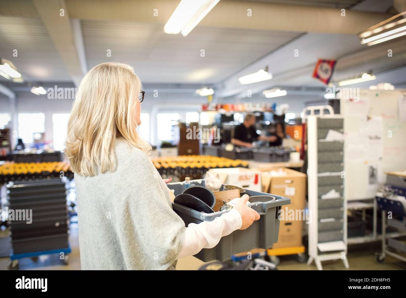Mujer con pelo rubio llevando caja en el taller Foto de stock