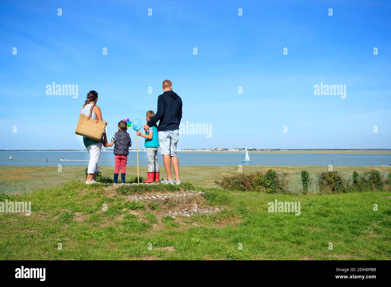 La bahía de Somme (norte de Francia): una familia con dos hijos, frente al mar, mirando a un velero en el agua, en Saint-Valery-sur-Somme, a lo largo de la costa Foto de stock