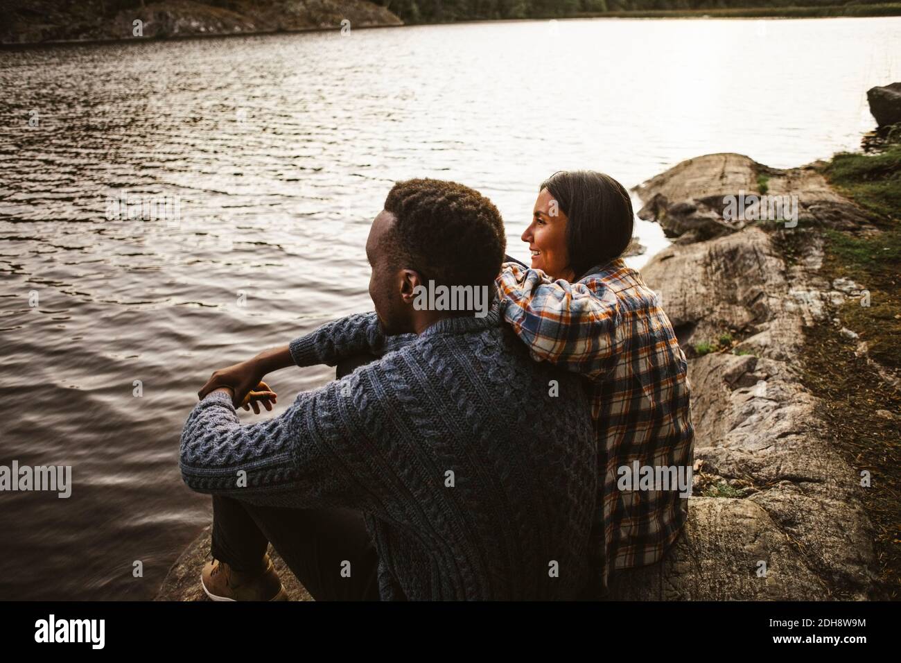 Vista lateral del hombre y la mujer sentados en el lago bosque Foto de stock