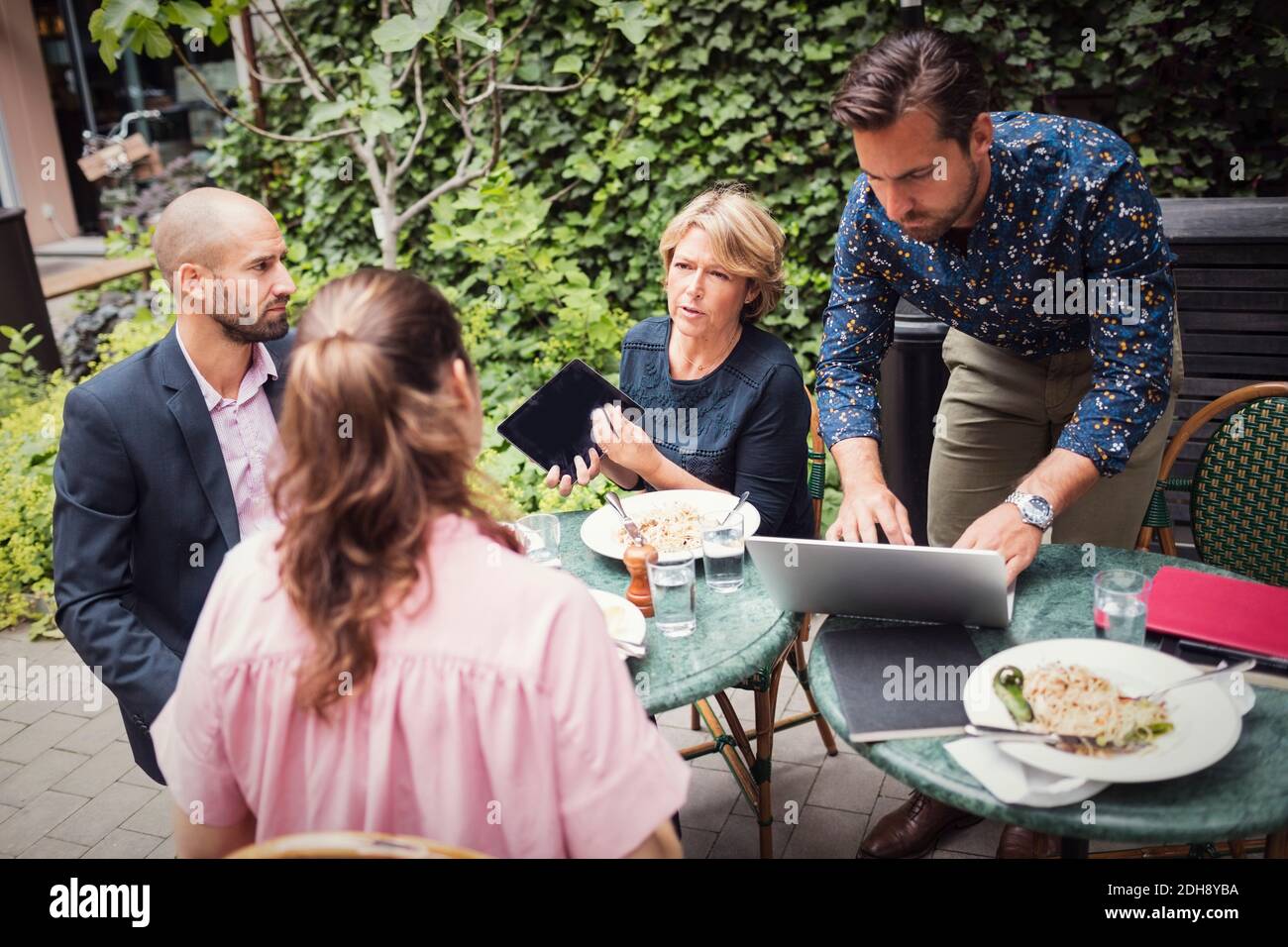 Gente de negocios discutiendo mientras come en el patio de oficinas Foto de stock