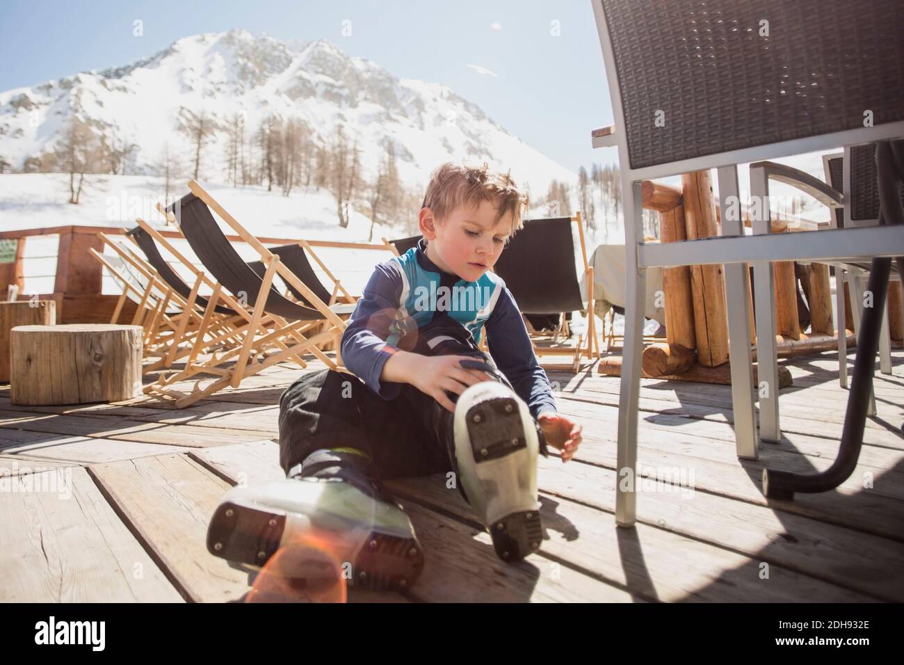 Niño con botas de esquí sentado en el suelo Foto de stock