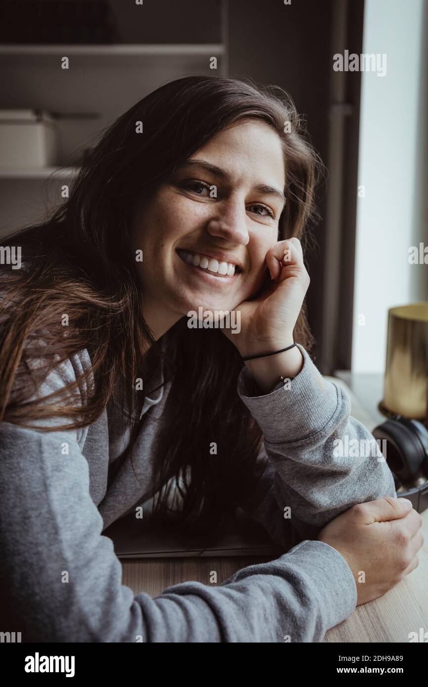 Retrato de una mujer sonriente en la mesa Foto de stock