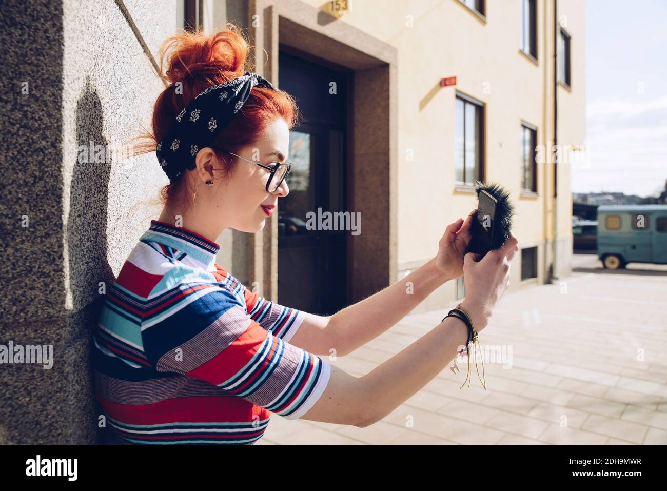 Joven mujer hipster tomando selfie mientras que está de pie contra la pared Foto de stock