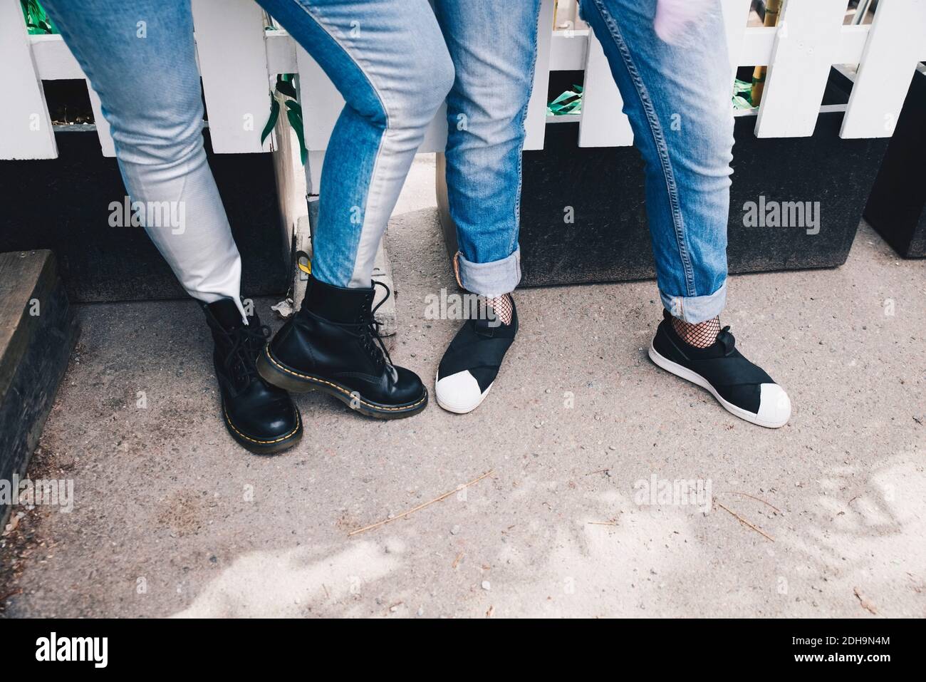 Sección baja de las amigas que usan jeans mientras están de pie cerca Foto de stock