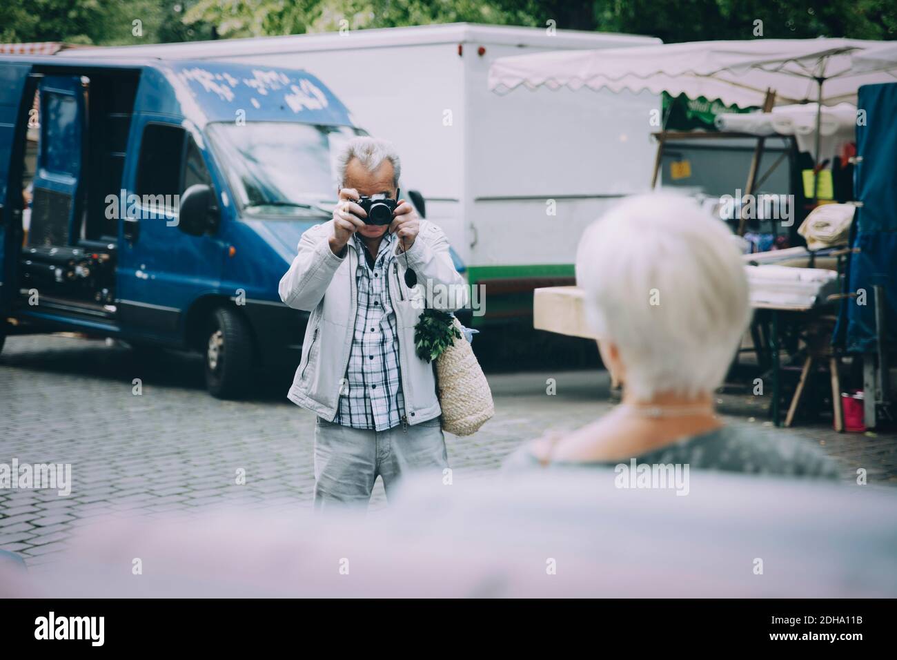Turista mayor tomando fotografía de mujer mientras está de pie en la ciudad Foto de stock